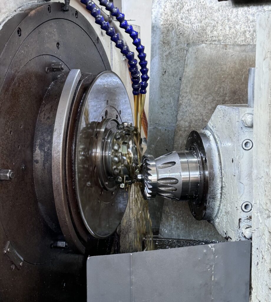 This is the core machining stage. The CNC machine is high-speed cutting a steel blank into a precise spiral tooth shape. The oil being sprayed serves as a coolant and lubricant to prevent tool overheating and improve surface finish.